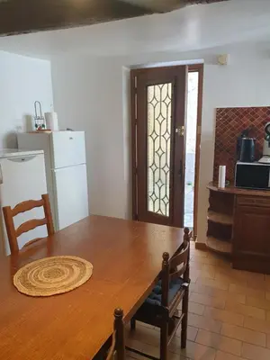 a kitchen with a wooden table and a refrigerator at Charmante maison de village au cœur du Luberon in Pierrevert