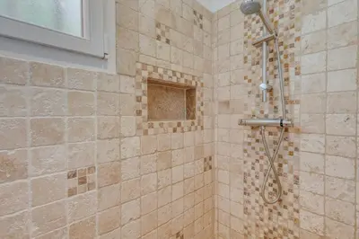 a shower with a shower head in a bathroom at Le JARDIN DES DELIS gite NEUF avec piscine bio UV in Saint-Saturnin-les-Apt