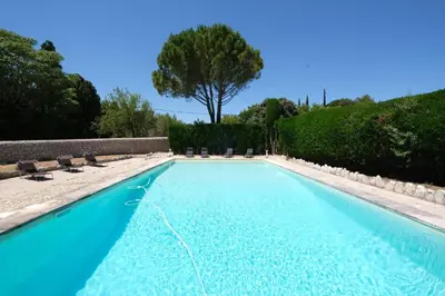 a blue swimming pool with chairs and a tree at typical mas provençal with swimming pool in a small hamlet near mouriès in the alpilles in provence- 8 persons in Mouriès