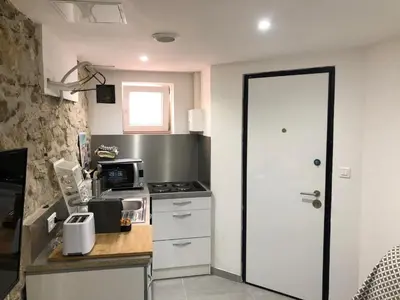 a small kitchen with a stove and a white door at Les Olives Wifi Netflix Appart-hotel-Provence in La Fare-les-Oliviers
