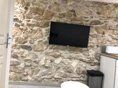 a stone wall with a flat screen tv on it at Les Olives Wifi Netflix Appart-hotel-Provence in La Fare-les-Oliviers