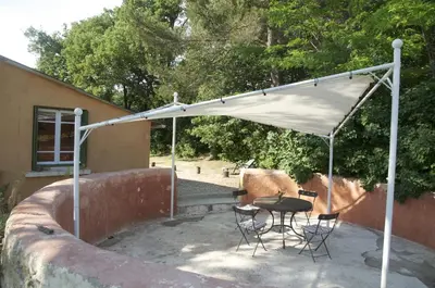 a patio with a table and chairs under a white canopy at Le petit Bacalan in Mormoiron