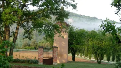 a building in the middle of a field with trees at Le petit Bacalan in Mormoiron