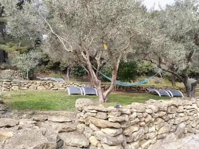 a stone wall with chairs and a tree and trees at Gîte du domaine de l'Arbre de Vie in Saint-Chamas