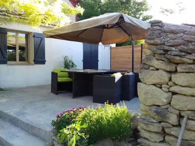 a patio with an umbrella next to a stone wall at Gîte du domaine de l'Arbre de Vie in Saint-Chamas
