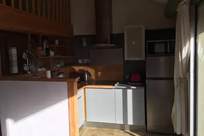 a kitchen with white cabinets and a stainless steel refrigerator at Duplex lumineux sur gde TERRASSE, BALNEO double, parking privé, CLIM, local vélos in Entraigues-sur-la-Sorgue