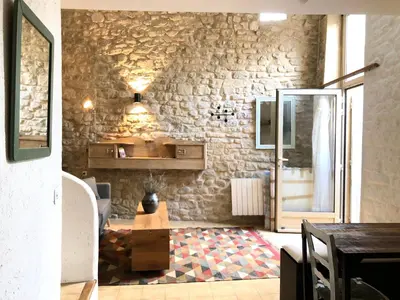 a living room with a stone wall and a table at Studio 57 à Saignon in Saignon