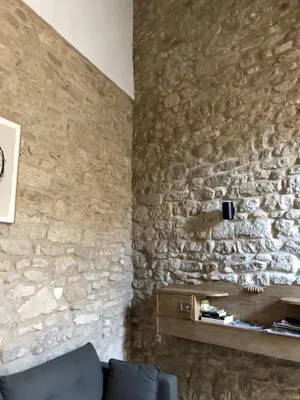a living room with a stone wall and a couch at Studio 57 à Saignon in Saignon