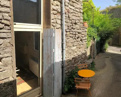 a table and a bench next to a stone building at Studio 57 à Saignon in Saignon