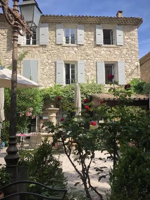 a large stone building with a tree and an umbrella at La Figuiere Fontaine de Vaucluse in Fontaine-de-Vaucluse