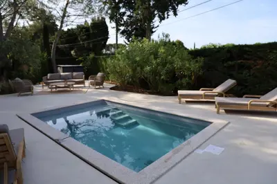 a swimming pool with chaise lounges and chairs around it at Villa moderne en Provence avec piscine in Carpentras