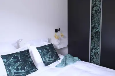 a bedroom with a white bed with green and white pillows at Le Galinié Chic'Art. Un bel Atelier avec Piscine in Carpentras