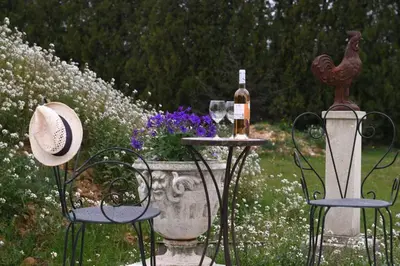 a table with a bottle of wine and two chairs at Le Galinié Chic'Art. Un bel Atelier avec Piscine in Carpentras