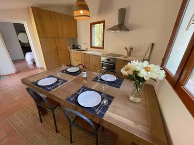 a wooden table with chairs and a vase of flowers at Mas de la Pivoine in Le Puy-Sainte-Réparade