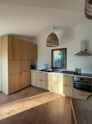 a kitchen with wooden cabinets and a sink and a window at Mas de la Pivoine in Le Puy-Sainte-Réparade