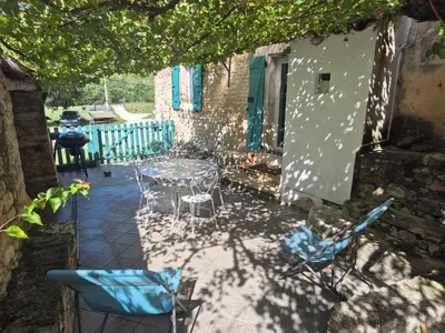 a patio with a table and chairs under a tree at Gite au cœur du Luberon in Goult