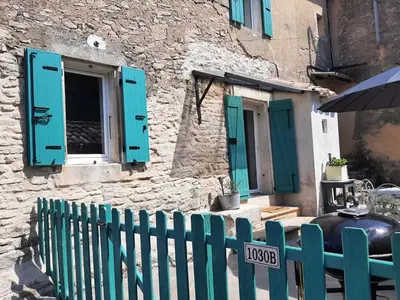 a house with blue shutters and a fence at Gite au cœur du Luberon in Goult