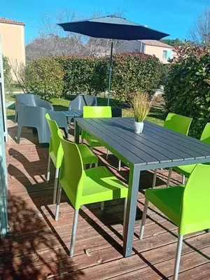 a wooden table with green chairs and an umbrella at Résidence Les Demeures du Ventoux in Aubignan