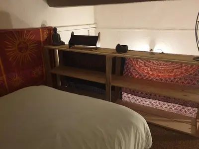 a bedroom with a bed and a shelf with a laptop on it at Charmant appartement cœur village provençal in Lambesc