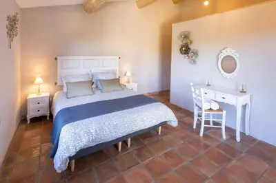 a bedroom with a bed and a table and a mirror at La Bastide des Milles in Apt
