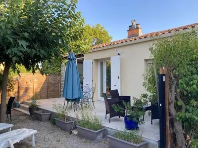 a patio with a table and chairs and an umbrella at Maison Avec jardin clôturé in LʼIsle-sur-la-Sorgue