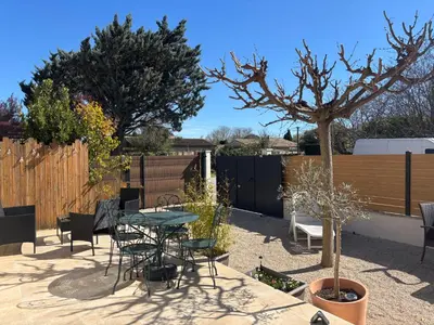 a patio with a table and chairs in front of a house at Maison Avec jardin clôturé in LʼIsle-sur-la-Sorgue