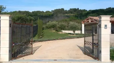 an iron gate with a garden in the background at L’Abrico’thym in Apt