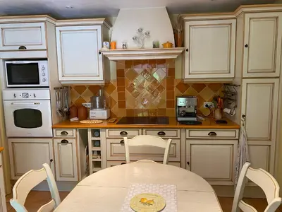 a kitchen with white cabinets and a table with chairs at Maison provençale en campagne à Eguilles in Éguilles