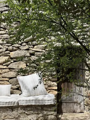a stone wall with two pillows and a tree at Le Mas de Béthel in Gordes