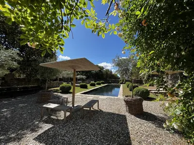 a bench and an umbrella next to a pool at Le Mas de Béthel in Gordes