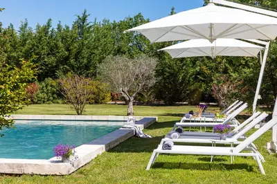 a couple of chairs and an umbrella next to a pool at La Bastide de Damien, 5 clefs Demeure d'Exception et Table Remarquable dans le guide Teritoria, JACUZZI Privatif, Cuisine étoilée Dominique Frérard in Aix-en-Provence