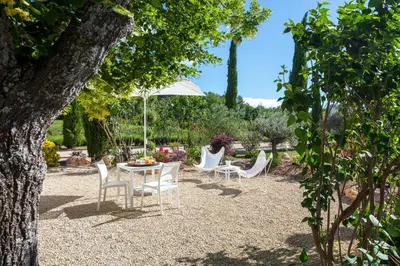 a patio with a table and chairs and an umbrella at La Bastide de Damien, 5 clefs Demeure d'Exception et Table Remarquable dans le guide Teritoria, JACUZZI Privatif, Cuisine étoilée Dominique Frérard in Aix-en-Provence