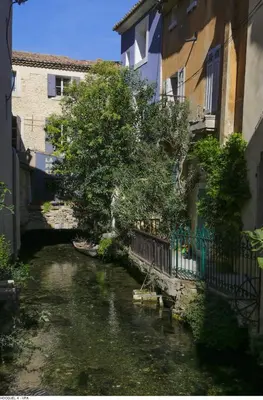 a river in front of a building next to a building at Maison de village façon Loft, avec cour et airco, dans le centre historique in LʼIsle-sur-la-Sorgue