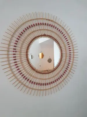 a circular mirror with red accents on a white wall at vintage home in LʼIsle-sur-la-Sorgue
