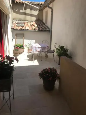 a patio with a table and chairs and potted plants at La Charmeuse in Céreste
