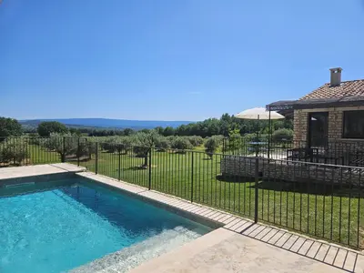 a fence around a swimming pool in a yard at Bastide Toujours Dimanche, Maison de vacances avec vue & piscine chauffée in Gordes