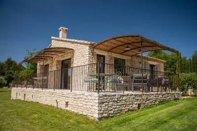 a stone house with a large deck on top at Bastide Toujours Dimanche, Maison de vacances avec vue & piscine chauffée in Gordes
