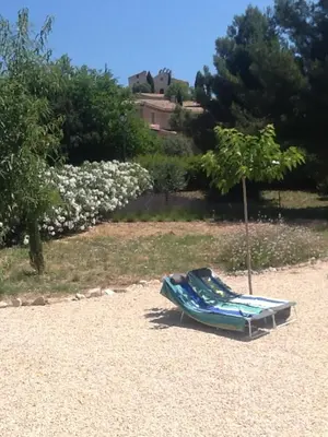 a beach chair sitting on the sand next to a tree at Le temps des cerises in Méthamis