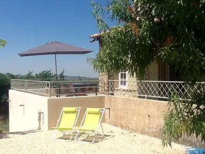 two lawn chairs and an umbrella on a building at Le temps des cerises in Méthamis