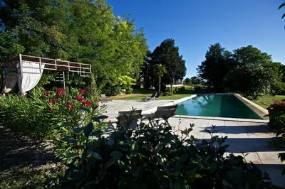 a swimming pool in a yard with chairs and flowers at Château des Cinq Cantons in Carpentras