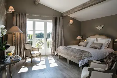 a bedroom with a large bed and a table and chairs at Château des Cinq Cantons in Carpentras