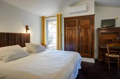 a bedroom with a large white bed and a desk at La Chaumière, Demeure d'hôtes in Lauris