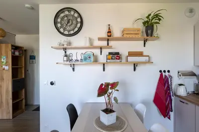 a kitchen with a table and a clock on the wall at Beau studio Monteux, balcon vue Lac, près de Spirou Provence in Monteux
