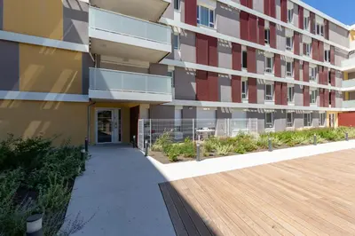 a building with a wooden walkway next to a building at Beau studio Monteux, balcon vue Lac, près de Spirou Provence in Monteux