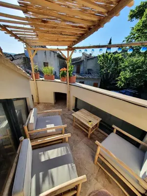 a patio with chairs and a table on a balcony at L'Exquishette de Lourmarin, un nid sur les toits. in Lourmarin