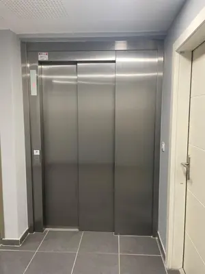 a metal elevator door in a room with a tile floor at Appartement et Garage au Cœur de l'Isle in LʼIsle-sur-la-Sorgue