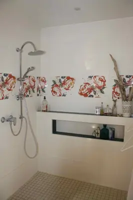 a bathroom with a shower with flowers on the wall at À l'ombre du mûrier in Blauvac