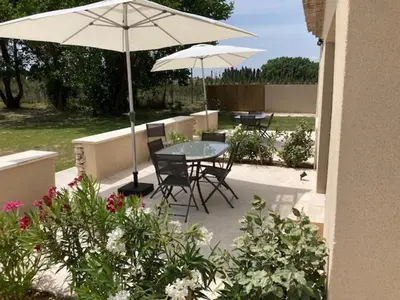 a patio with a table and chairs and an umbrella at Mas Galinette in Saint-Andiol