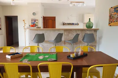 a dining room with a wooden table and yellow chairs at Maison Le Grand Verger in Goult