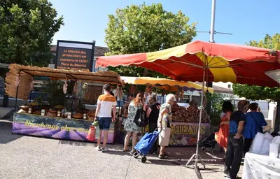 a group of people standing around a market with an umbrella at Chez Mamou & Dadou in Monteux